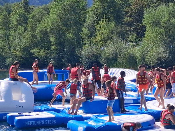 Immendatdt b - Wasserspaß Eine Gruppe Kinder ist mit roten Schwimmwesten auf den Neptune Steps zu sehen, eine Art Luftpolster auf einem See
