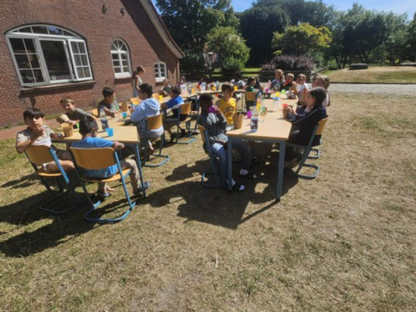 Neuwerk 2 - vierte Mahlzeit Eine Gruppe Kinder sitzt vor einem großen rot geklinkertem Gebäude und macht Pause