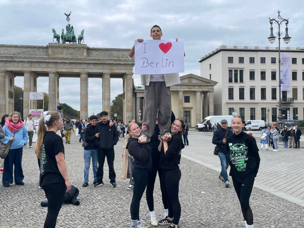 Kids in Berlin Jugendliche stehen vor Siegessäule in Berlin, zwei Mädchen haben einen Jungen hochgehoben der ein Schild mit der Aufschrift I love Berlin hochhält