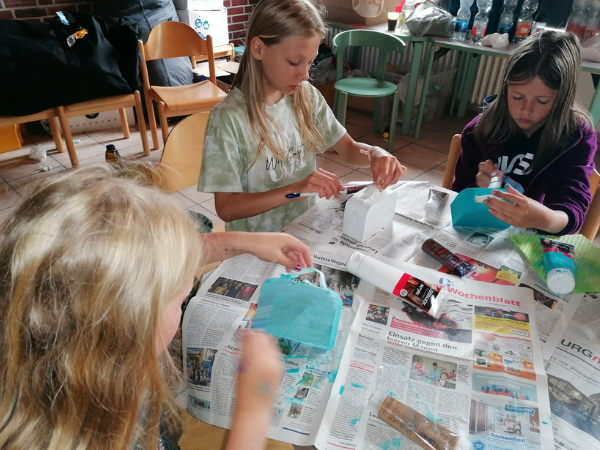 Action und Art 2 Drei Mädchen sitzen an einem Tisch und basteln